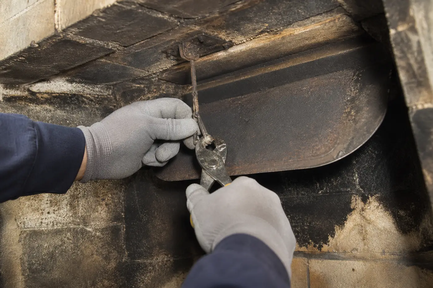Close-up detail of the metal fireplace damper and operating mechanism being repaired in Greater Boston